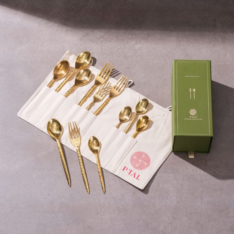 Brass cutlery set with spoons and forks arranged in a roll pouch beside green gift box