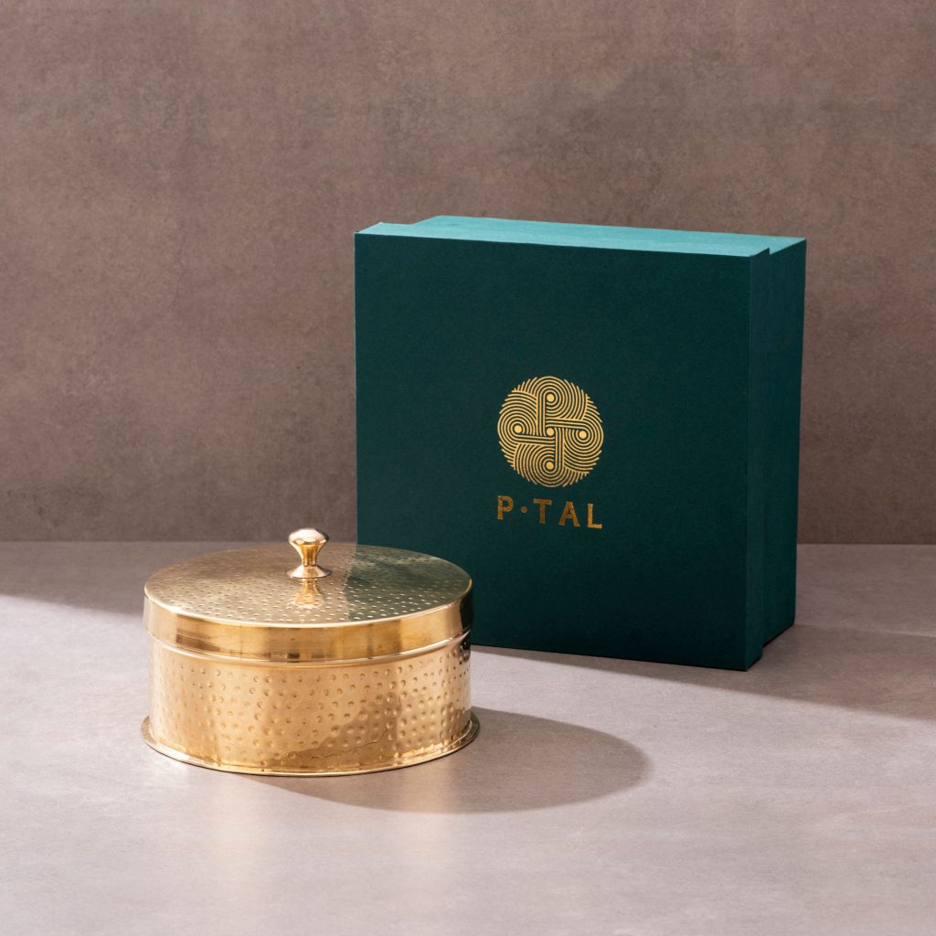 Brass storage box with lid displayed beside green gift box