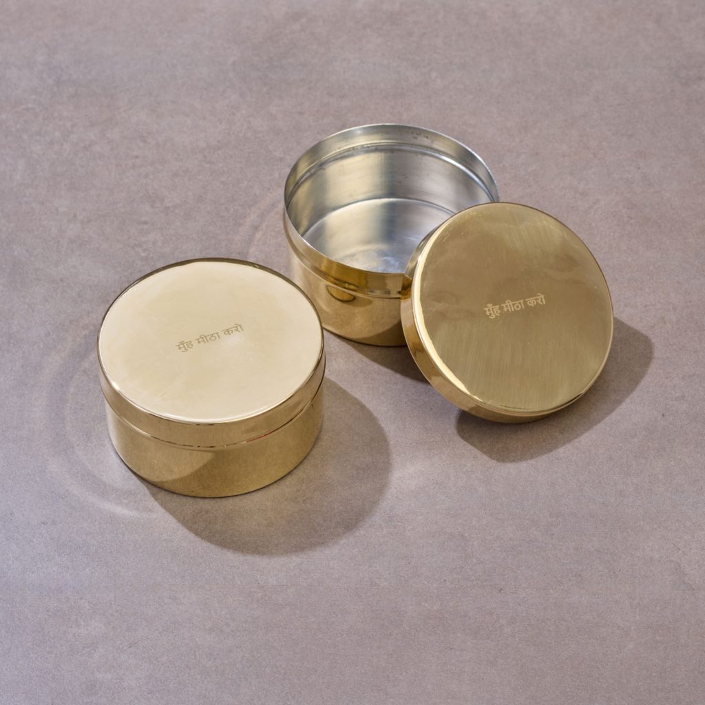 Brass storage containers with lids arranged on textured studio surface