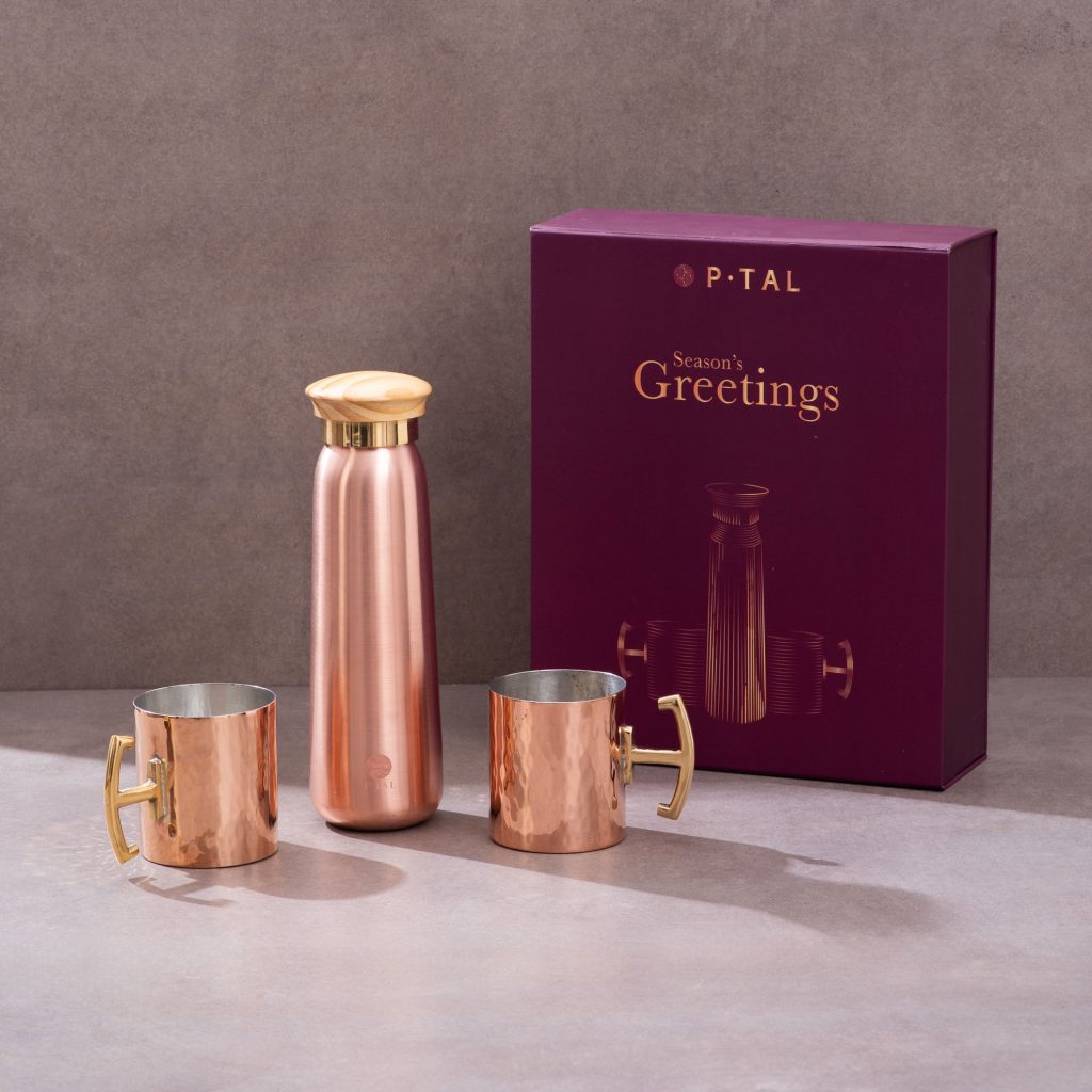 Copper bottle and hammered copper mugs displayed with maroon festive gift box