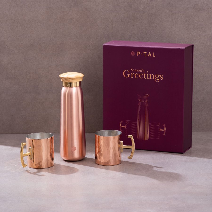 Copper bottle and hammered copper mugs displayed with maroon festive gift box