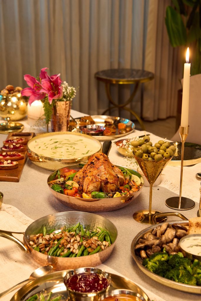 Copper and brass cookware styled on dinner table with food, candles and flowers