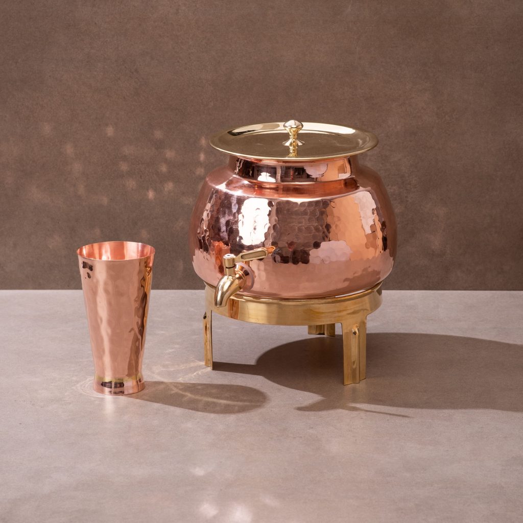 Hammered copper water dispenser with brass tap, lid, stand and matching glass