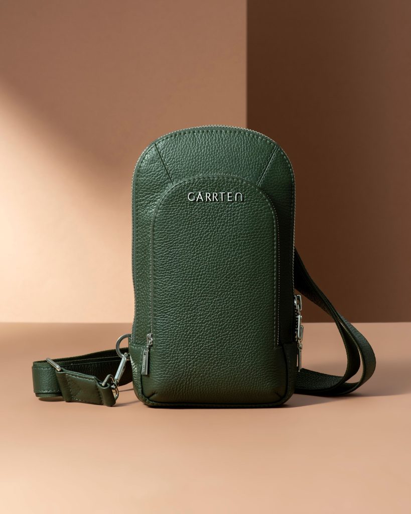 Green leather sling bag with front zipper pocket and shoulder strap.