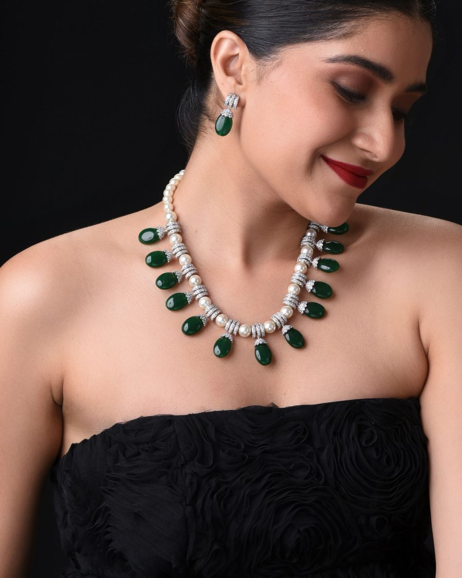 Model wearing pearl necklace, bracelet, and earrings with magenta outfit.