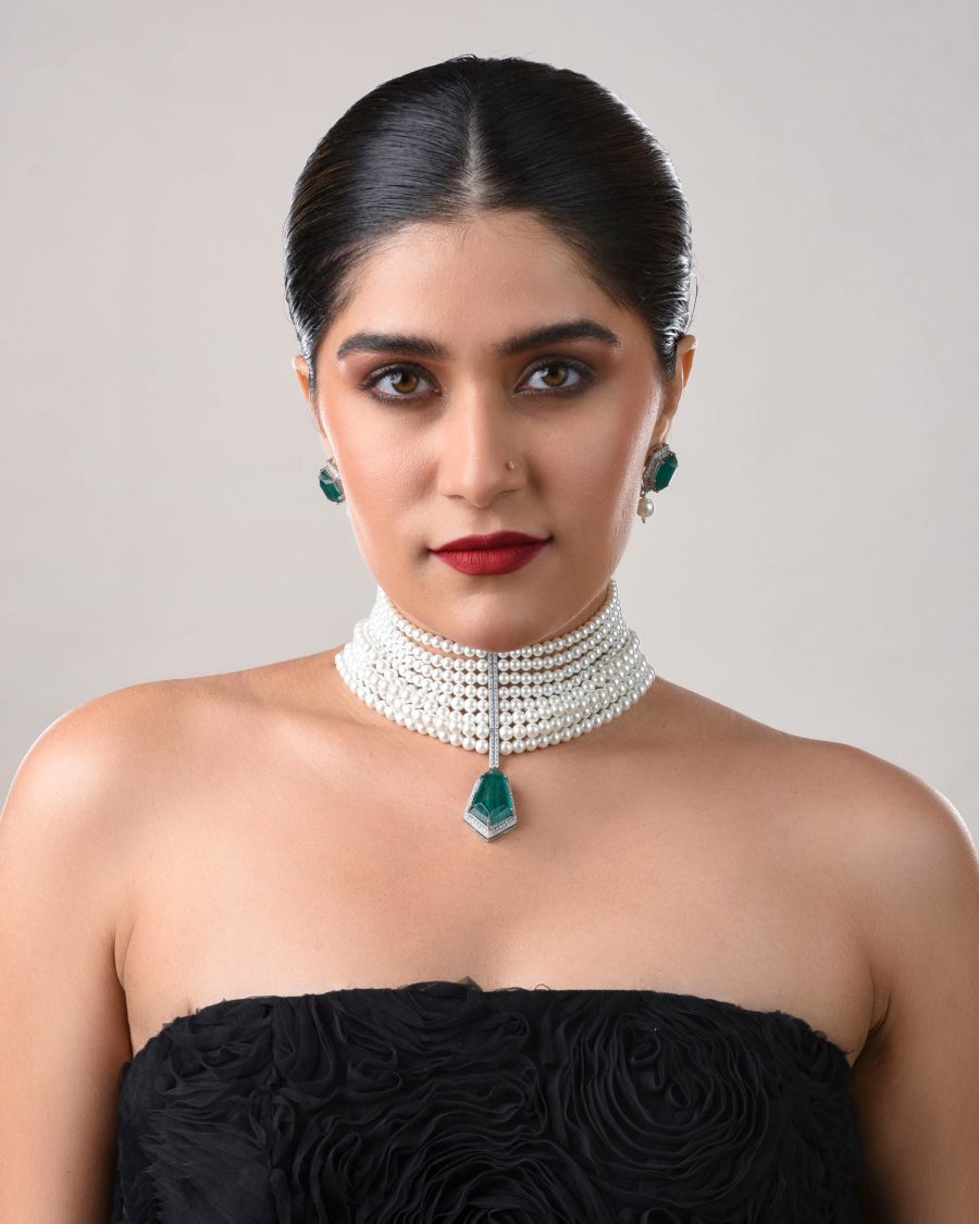 Model wearing pearl choker with green pendant and matching green earrings.