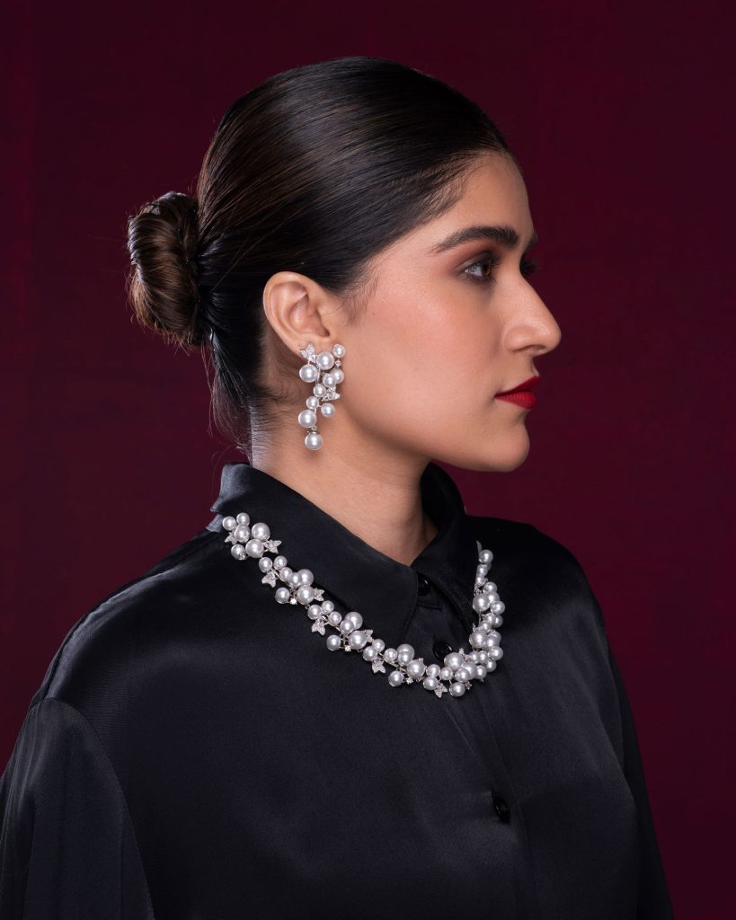 Side profile of model wearing pearl drop earrings and pearl necklace.