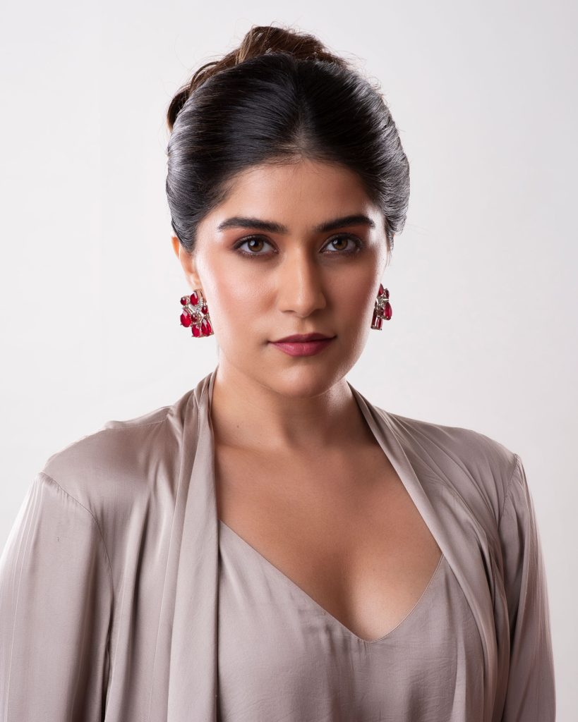 Model wearing red stone earrings in a studio jewellery portrait.